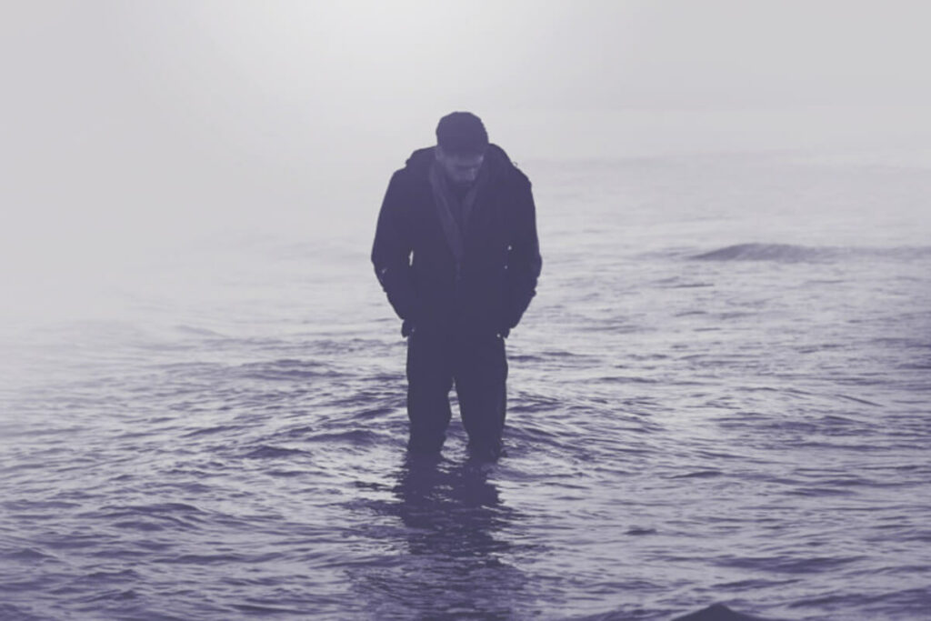 A lonely and devastated man standing in a lake of water.